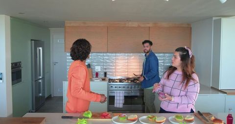 Housemates preparing sandwiches at modern open-plan kitchen island, cooking together