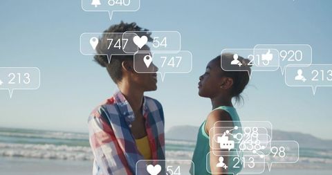 Black mother and daughter sharing seaside moment with social media notification overlays