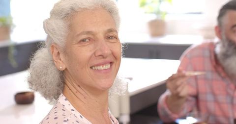 Smiling Senior Woman Sharing Meal with Friend at Home