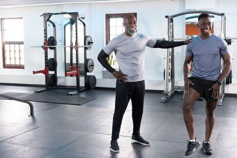 African american trainer coaching client performing knee lift mobility drill in gym