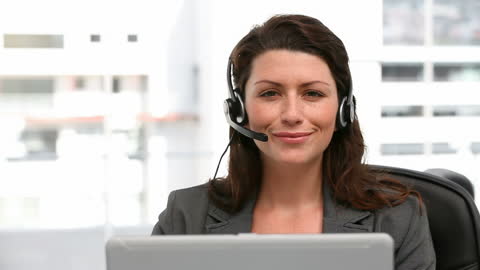 Friendly Call Center Operator Assisting Clients at Office Desk
