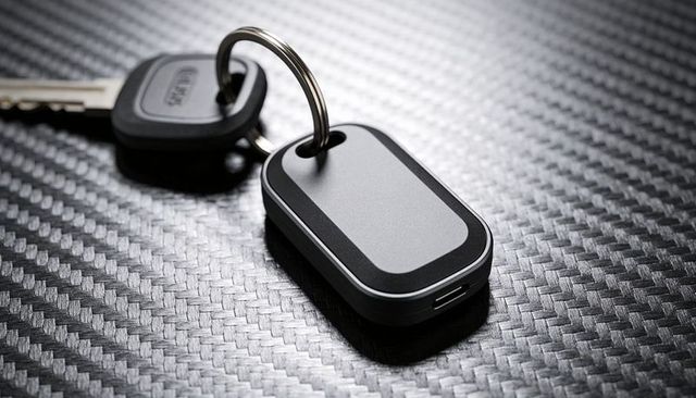 Smart key fob sitting on carbon fiber surface with metal key and usb port