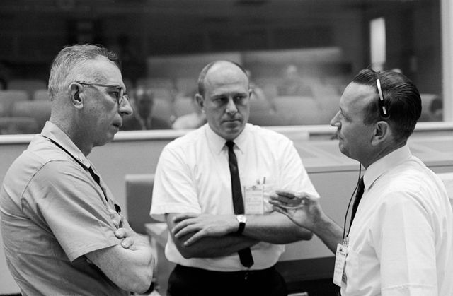 S65-28734 (24 Aug. 1965) --- Rear Admiral W.C. Abhau (left), who will take over command of Task Force 140 for Gemini-6, is shown in the Mission Control Center being briefed on recovery operations for Gemini by Robert F. Thompson (center), NASA recovery coordinator; and Christopher C. Kraft Jr., flight director for Gemini-5.
