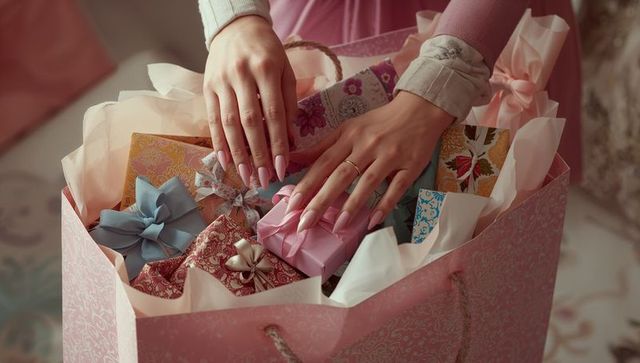 Elegant Hands Arranging Gift Boxes in Pastel Bag