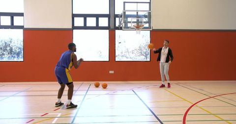 Coach and player practicing basketball skills on indoor gym court