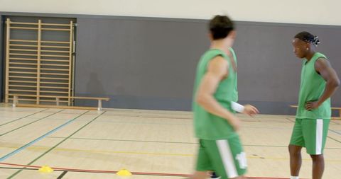 African american player practicing dribbling drill around cones in indoor basketball gym