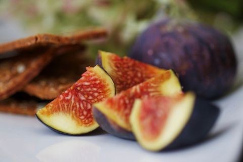 Fresh sliced figs with seeded crackers on white surface