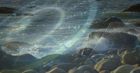 Sunlit blue-green waves crashing on rocky shore with wet pebbles and creative overlay
