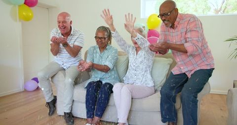 Senior group celebrating at home party with balloons and laughter