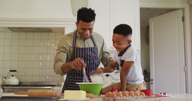 African american father and son baking together in the kitchen at home. family, love and togetherness concept