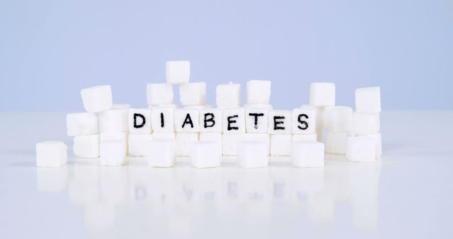 Sugar cubes are arranged to spell out 'DIABETES' against a plain background, with copy space. It symbolizes the connection between sugar consumption and the risk of developing diabetes.