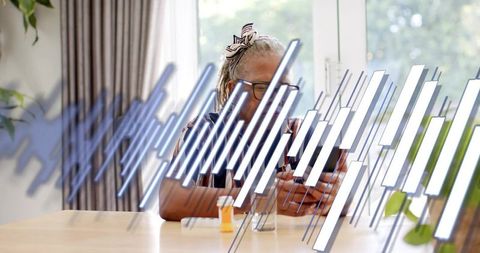 Senior Woman Managing Medication with Smartphone in Sunlit Home Kitchen