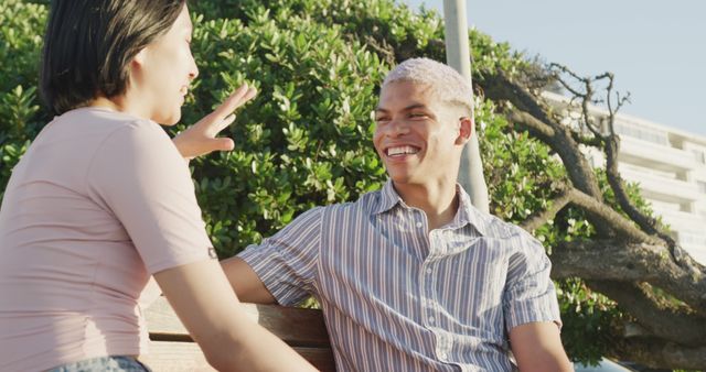 Group of young friends enjoying time outdoors, engaging in a lively conversation on a sunny day. Ideal for use in ads promoting social activities, friendship, youth culture, or outdoor events. Can also be used in blogs or articles related to lifestyle, leisure, and relationships.