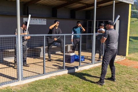 Baseball team warming up in dugout while batter taking practice swings before game