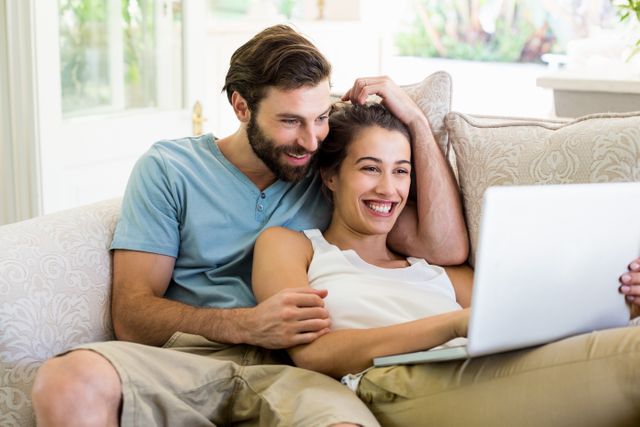 Couple sitting on sofa and using laptop - Download Free Stock Photos Pikwizard.com