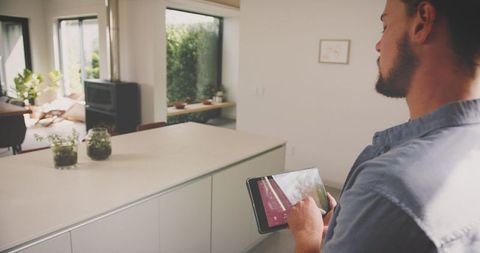 Man using tablet for smart home control in modern kitchen