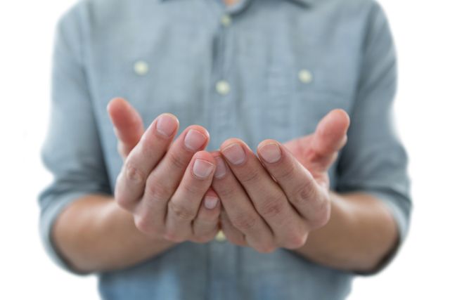 This image shows a close-up of a man's cupped hands, as if holding an invisible object, against a white background. It can be used in contexts related to offering, giving, receiving, or presenting something. Ideal for use in advertisements, presentations, or articles discussing concepts of generosity, support, or emptiness.