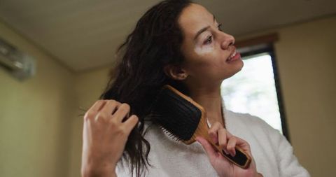 Biracial Woman Brushing Hair in Bathrobe at Home