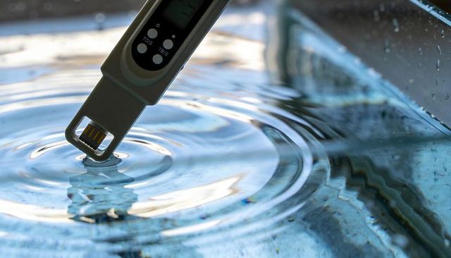 Tds meter probe measuring water quality creating ripples in glass container close-up macro