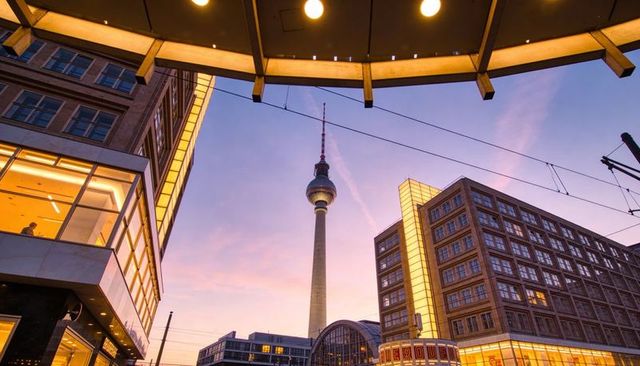 Berlin tv tower rising above alexanderplatz at golden sunset under station canopy