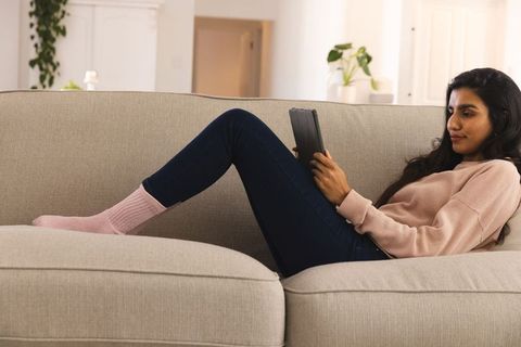 Woman Relaxing on Sofa Using Tablet in Bright Living Room