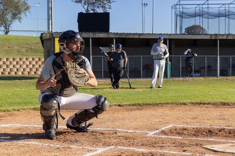 Baseball catcher crouching at home plate receiving pitch with animated arc
