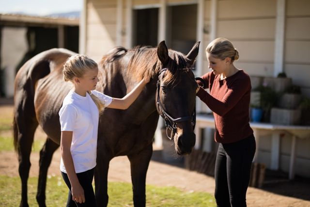 Mother and daughter touching the horse on a sunny day