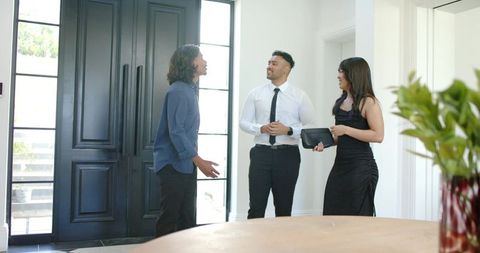 African american couple meeting realtor in modern foyer discussing home purchase