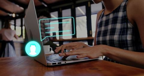 Young woman typing on laptop in coffeehouse with holographic chat bubble and avatar