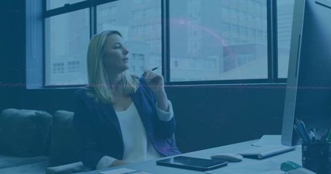 Executive woman gazing out window from modern office desk with tablet and pen in hand