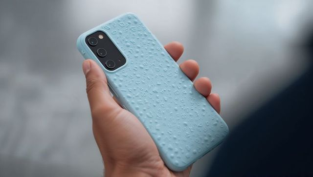 Hand holding blue silicone phone case with water droplet texture and triple camera closeup
