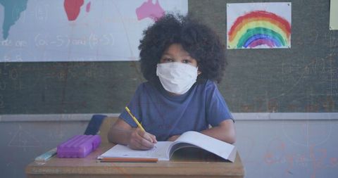 Schoolboy wearing mask learning math during pandemic