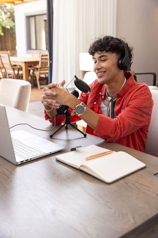 Hispanic man podcasting from home office with usb microphone