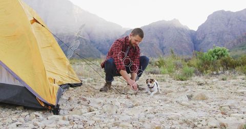 Hiker Setting Up Camp with Dog in Rocky Mountain Landscape