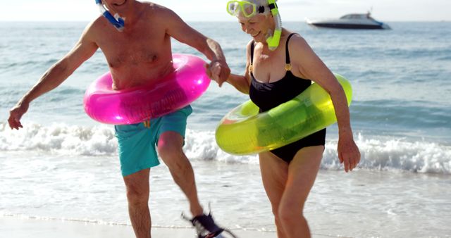 Happy Senior Couple Enjoying Beach with Snorkeling Gear and Float Rings - Download Free Stock Images Pikwizard.com