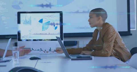 Leaning analyst studying laptop and monitor charts in collaborative data analytics meeting