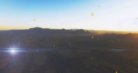 Mountains Silhouetted Against Sunrise Horizon With Lens Flare