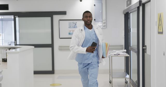 Confident Doctor Walking Quickly Through Hospital Corridor Holding Documents and Phone - Download Free Stock Images Pikwizard.com