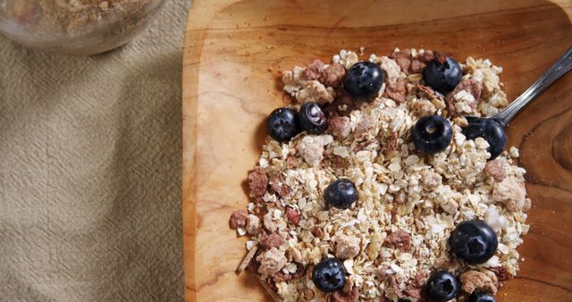 A bowl of oatmeal topped with blueberries and granola sits on a table, offering a nutritious breakfast option. This meal is a healthy choice for starting the day with a balance of fiber, antioxidants, and whole grains.