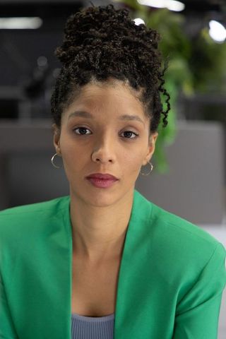 Confident african american professional woman wearing green blazer looking forward