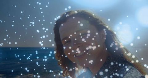 Smiling woman backlit by sun at ocean horizon with bokeh lens flare and rim light