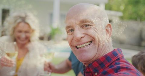 Smiling bald man taking selfie at backyard family gathering with wine and pool