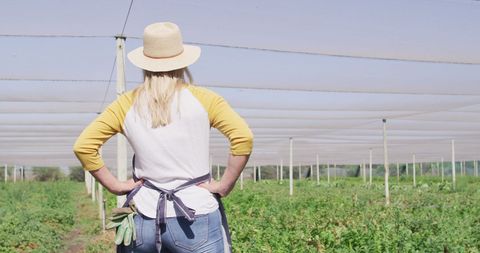 Female Farmer Overlooking Thriving Greenhouse Crops