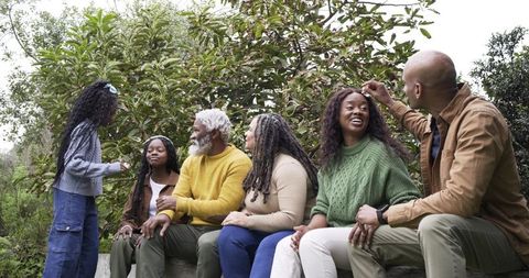 Multigenerational Family Relaxing on Garden Wall Sharing Leaf and Laughing Together