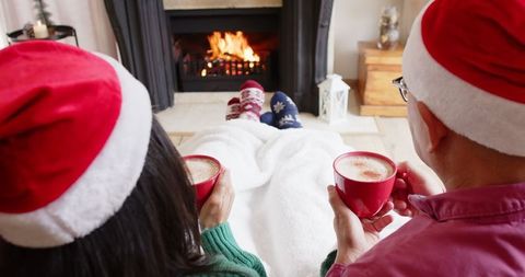Cozy Holiday Scene with Couple by Fireplace and Santa Hats