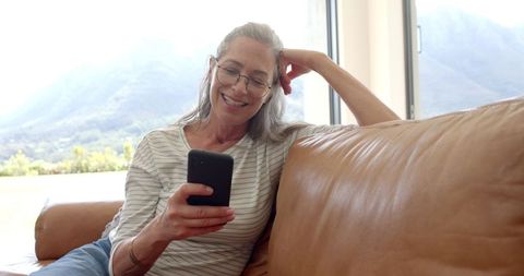 Mature Woman Relaxing at Home Using Smartphone
