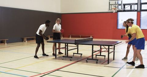Diverse Couples Playing Doubles Table Tennis in Gym