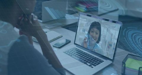 Remote video call in home office with woman on laptop screen, desk workspace and charts