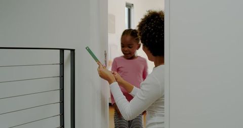 Mother and daughter measuring growth together at home