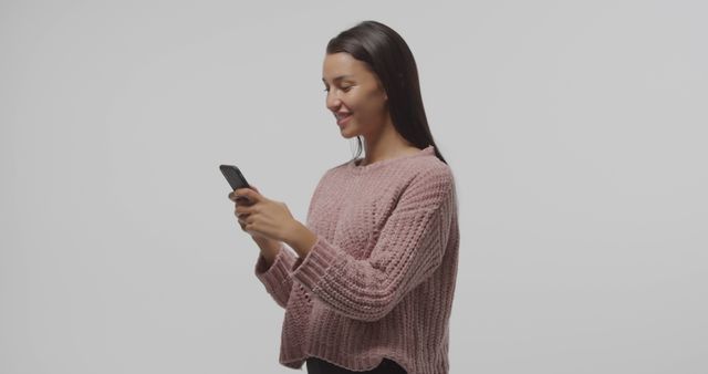 Smiling Woman Typing on Phone in Casual Sweater - Download Free Stock Images Pikwizard.com